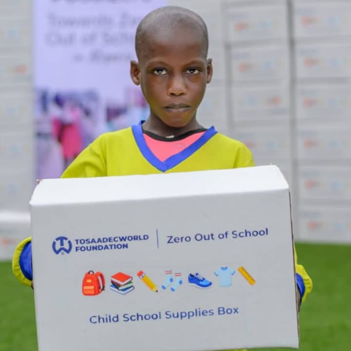 A child holding a TosaadecWorld Foundation Child School Supplies Box